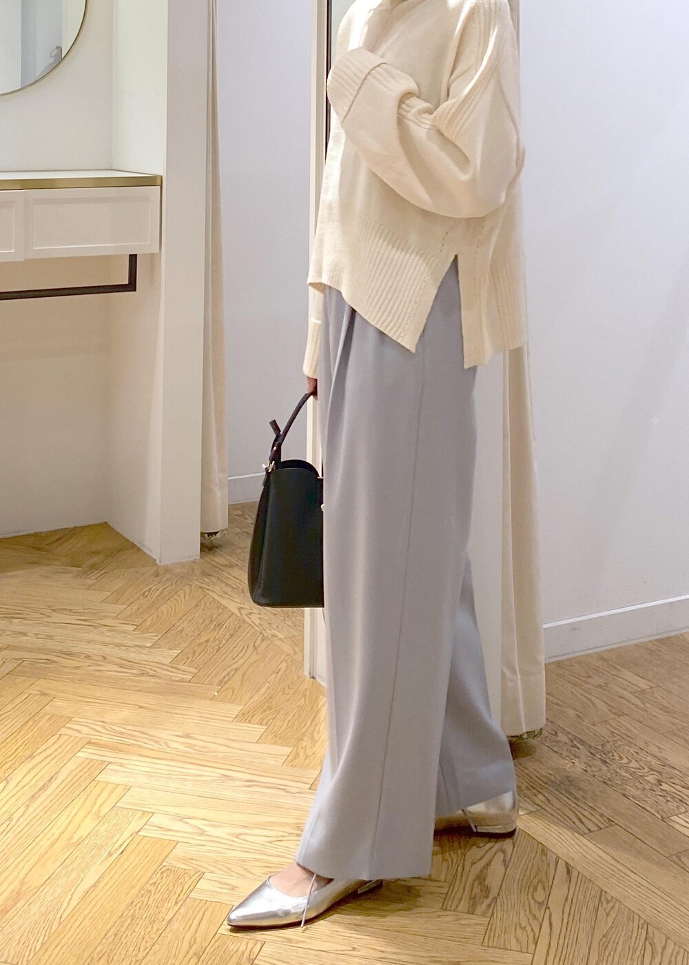 シルバー系のパンプス、ブラック系のショルダーバッグ、ブルー系のスラックスを着用したレディースの秋コーディネートの4枚目の写真