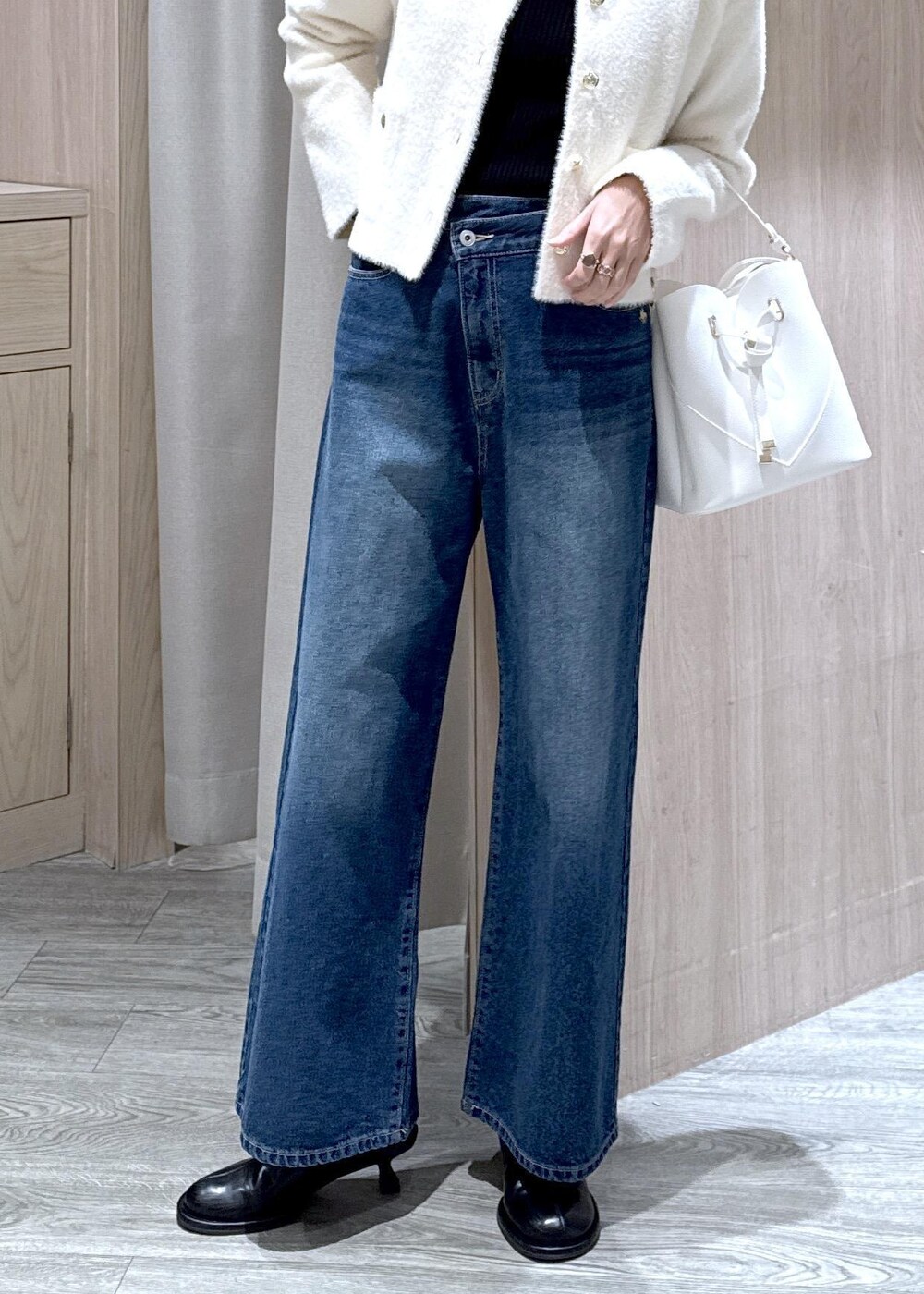 ホワイト系のショルダーバッグ、ブルー系のデニムパンツ、ブラック系のニット/セーターを着用したレディースの冬コーディネートの4枚目の写真