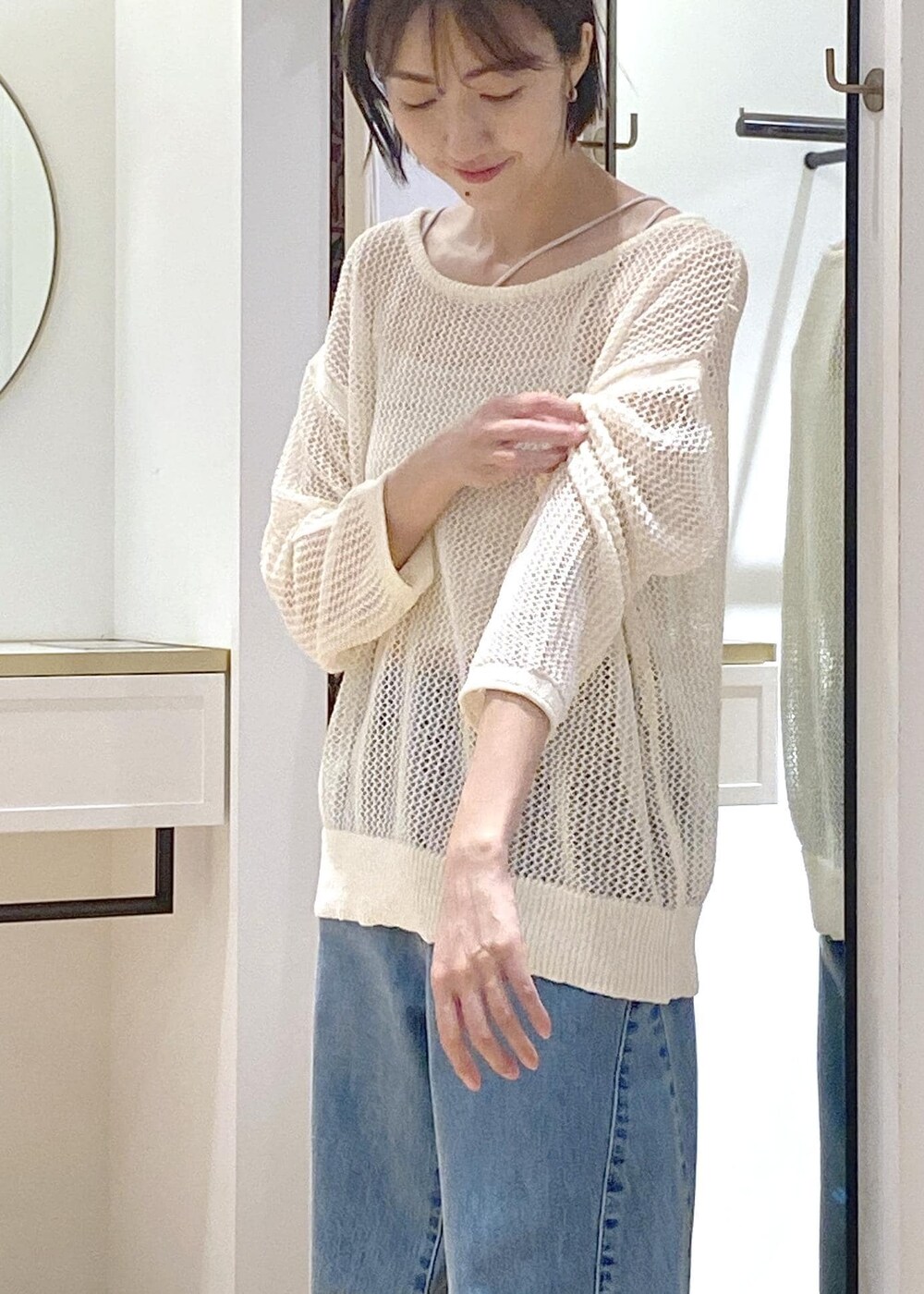 シルバー系のパンプス、シルバー系のトートバッグ、ブルー系のデニムパンツを着用したレディースの夏コーディネートの4枚目の写真