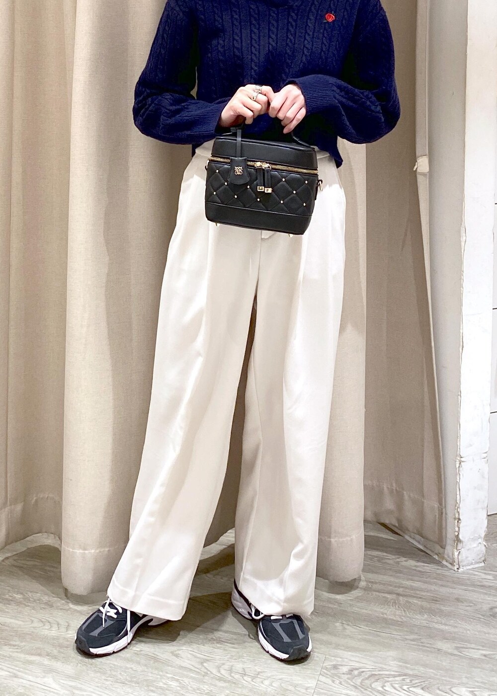 ブラック系のキャミソール、ブラック系のハンドバッグ、ホワイト系のスラックスを着用したレディースの冬コーディネートの5枚目の写真