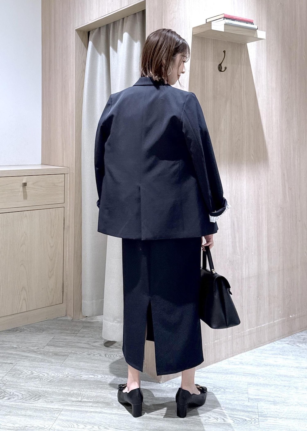 ブラック系のパンプス、ブルー系のテーラードジャケット、ブルー系のワンピースを着用したレディースの冬コーディネートの2枚目の写真