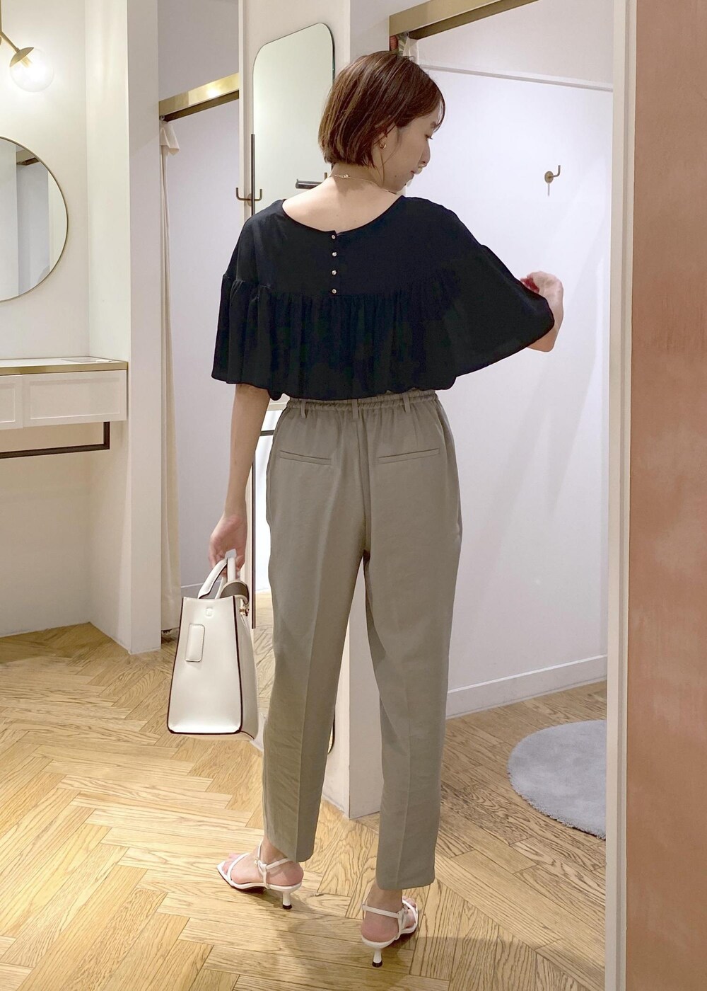 グリーン系のスラックス、ホワイト系のサンダル、ホワイト系のハンドバッグを着用したレディースの夏コーディネートの3枚目の写真