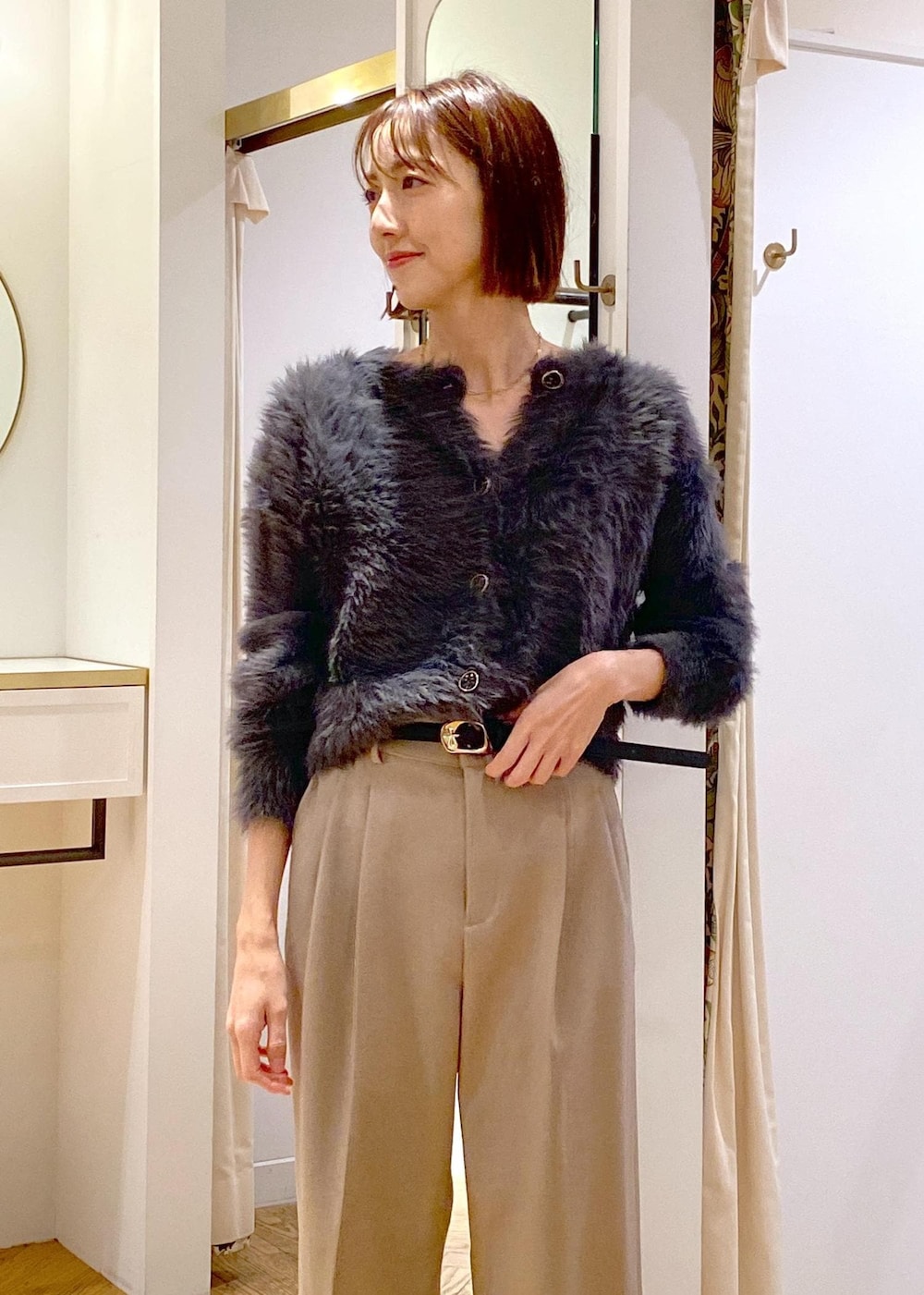 ホワイト系のショルダーバッグ、ベージュ系のスラックス、グレー系のカーディガン/ボレロを着用したレディースの冬コーディネートの9枚目の写真