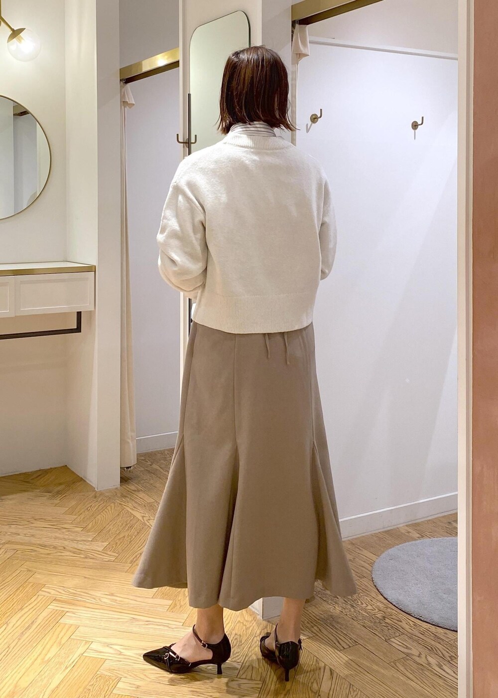 ブラック系のパンプス、ベージュ系のスカート、ホワイト系のシャツ/ブラウスを着用したレディースの冬コーディネートの3枚目の写真