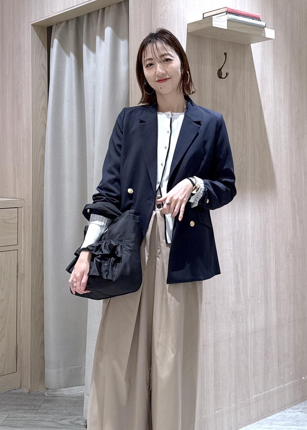 ブルー系のテーラードジャケット、ブラック系のトートバッグ、ホワイト系のカーディガン/ボレロを着用したレディースの冬コーディネートの2枚目の写真