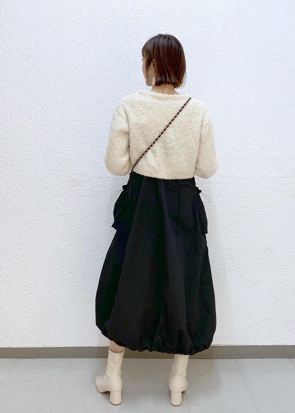 ホワイト系のTシャツ/カットソー、ブラック系のショルダーバッグ、ホワイト系のカーディガン/ボレロを着用したレディースの冬コーディネートの2枚目の写真