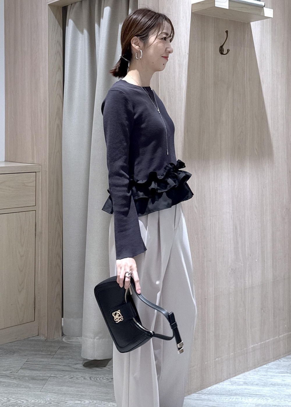 ブラック系のショルダーバッグ、ブラック系のパンプス、グレー系のニット/セーターを着用したレディースの春コーディネートの6枚目の写真