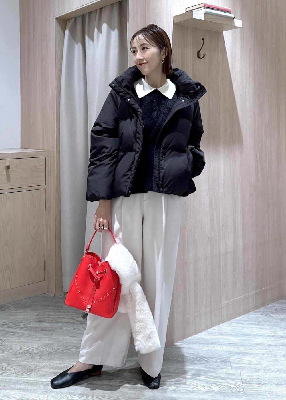 ブラック系のダウンジャケット/コート、ホワイト系のスラックス、ブラック系のニット/セーターを着用したレディースの冬コーディネートの2枚目の写真