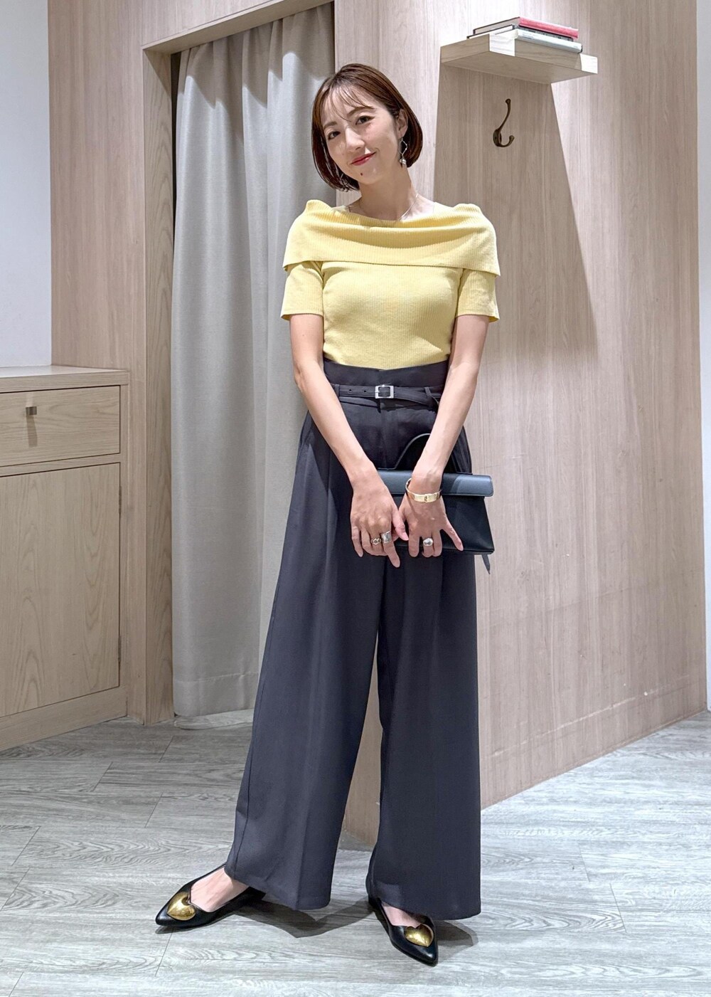 ブラック系のショルダーバッグ、ブラック系のバレエシューズ、イエロー系のニット/セーターを着用したレディースの夏コーディネートの4枚目の写真