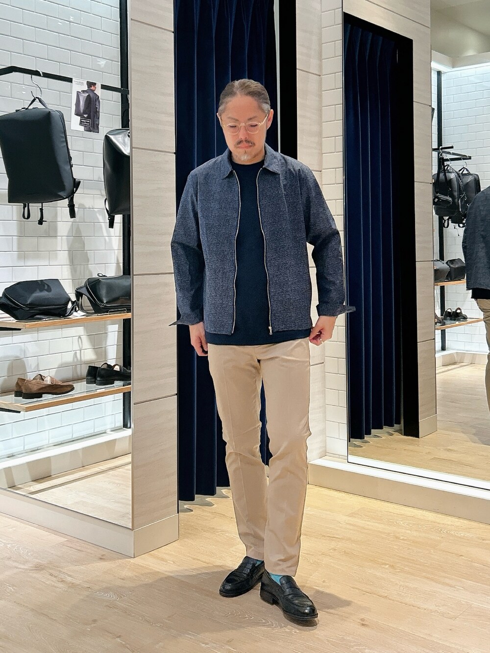 ブルー系のブルゾン、ブルー系のTシャツ/カットソー、ベージュ系のチノパンツを着用したメンズの春コーディネートの3枚目の写真