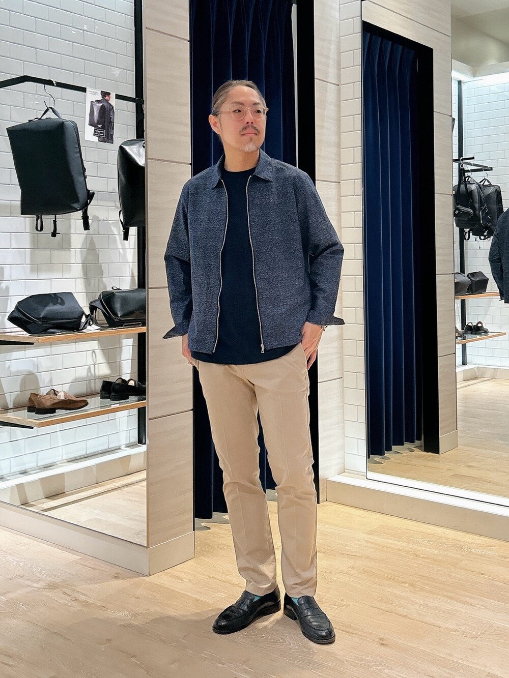 ブルー系のブルゾン、ブルー系のTシャツ/カットソー、ベージュ系のチノパンツを着用したメンズの春コーディネートの2枚目の写真