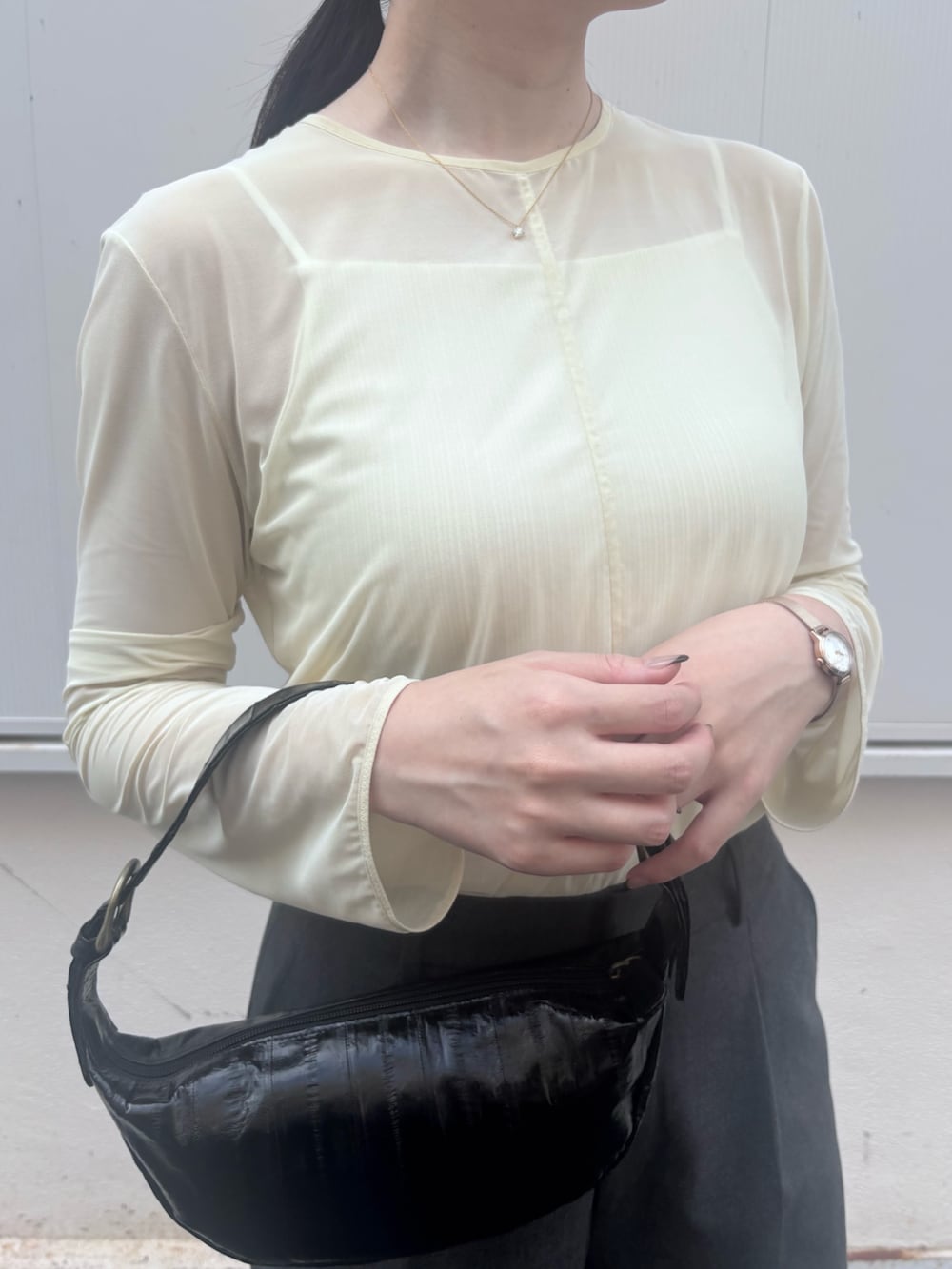 ホワイト系のトップス、グレー系のパンツ、ブラック系のショルダーバッグを着用したレディースの秋コーディネートの2枚目の写真
