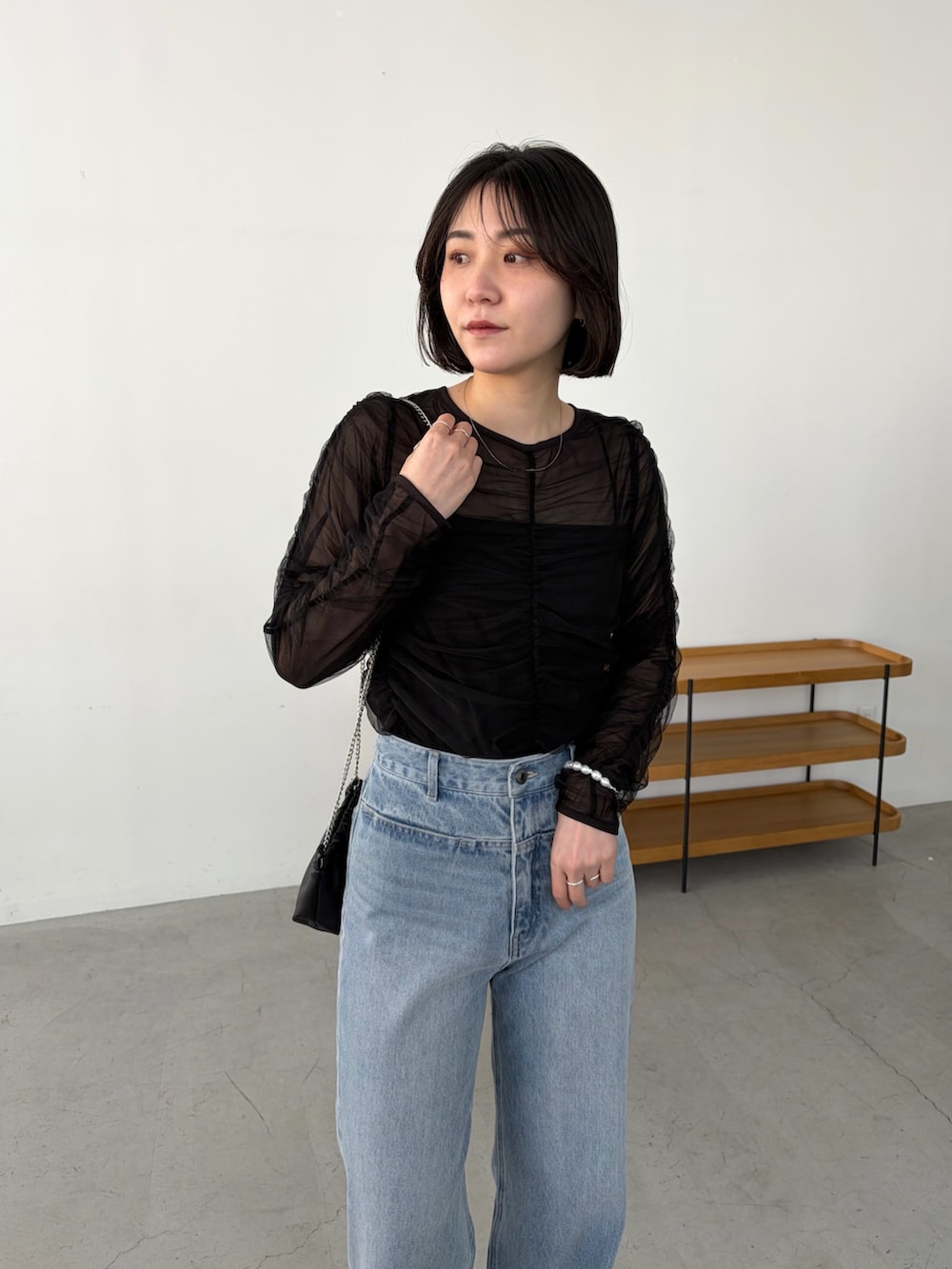 ブルー系のデニムパンツ、ブラック系のシャツ/ブラウス、ブラック系のショルダーバッグを着用したレディースの春コーディネートの2枚目の写真