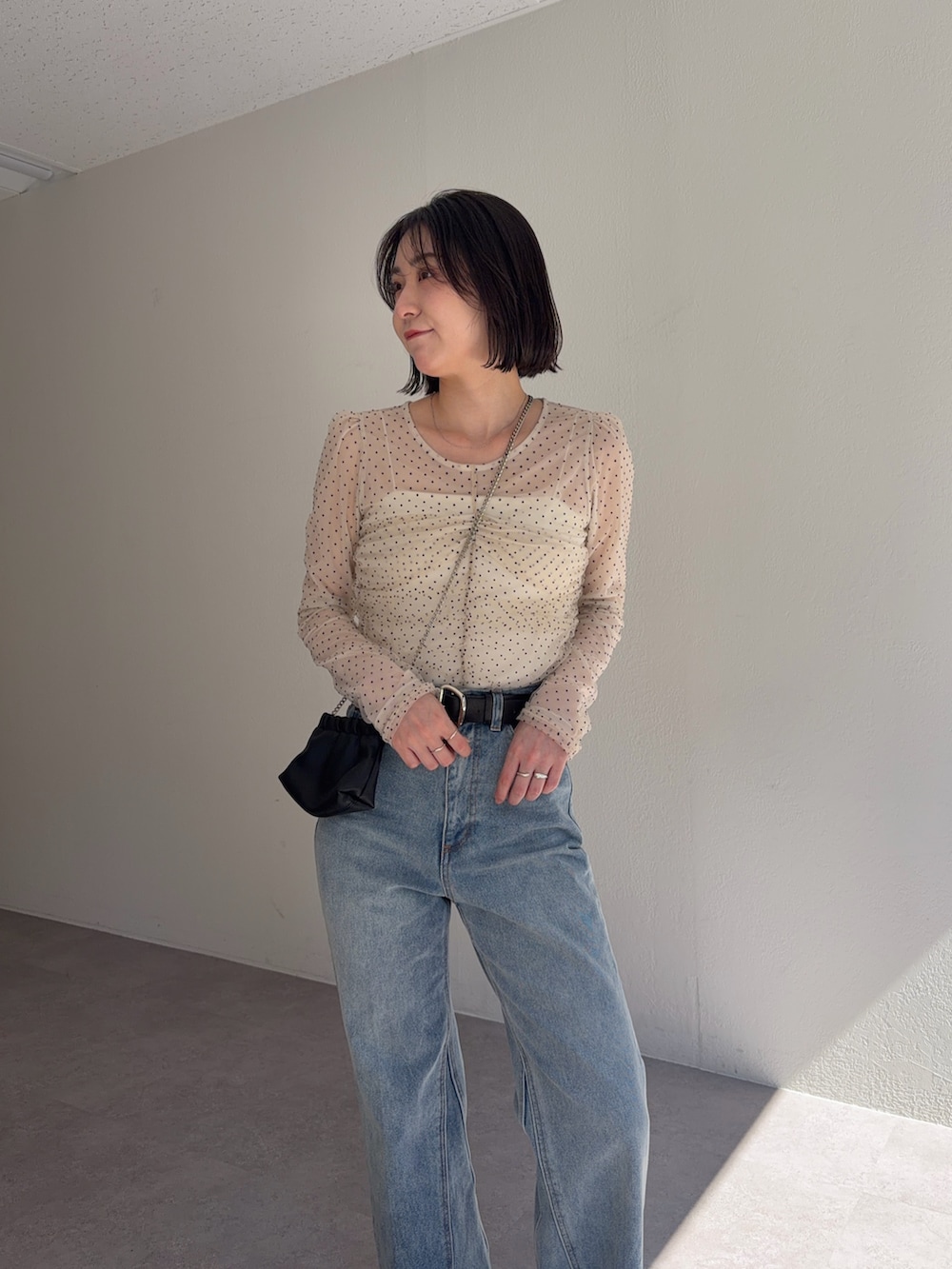 ブルー系のデニムパンツ、ブラック系のショルダーバッグ、ベージュ系のシャツ/ブラウスを着用したレディースの春コーディネートの2枚目の写真