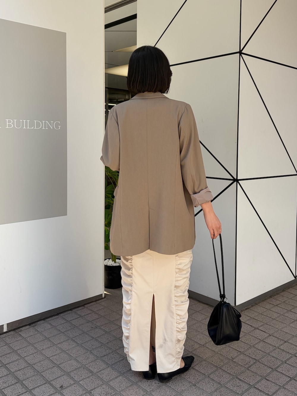 ホワイト系のワンピース、ベージュ系のテーラードジャケット、ブラック系のショルダーバッグを着用したレディースの冬コーディネートの6枚目の写真