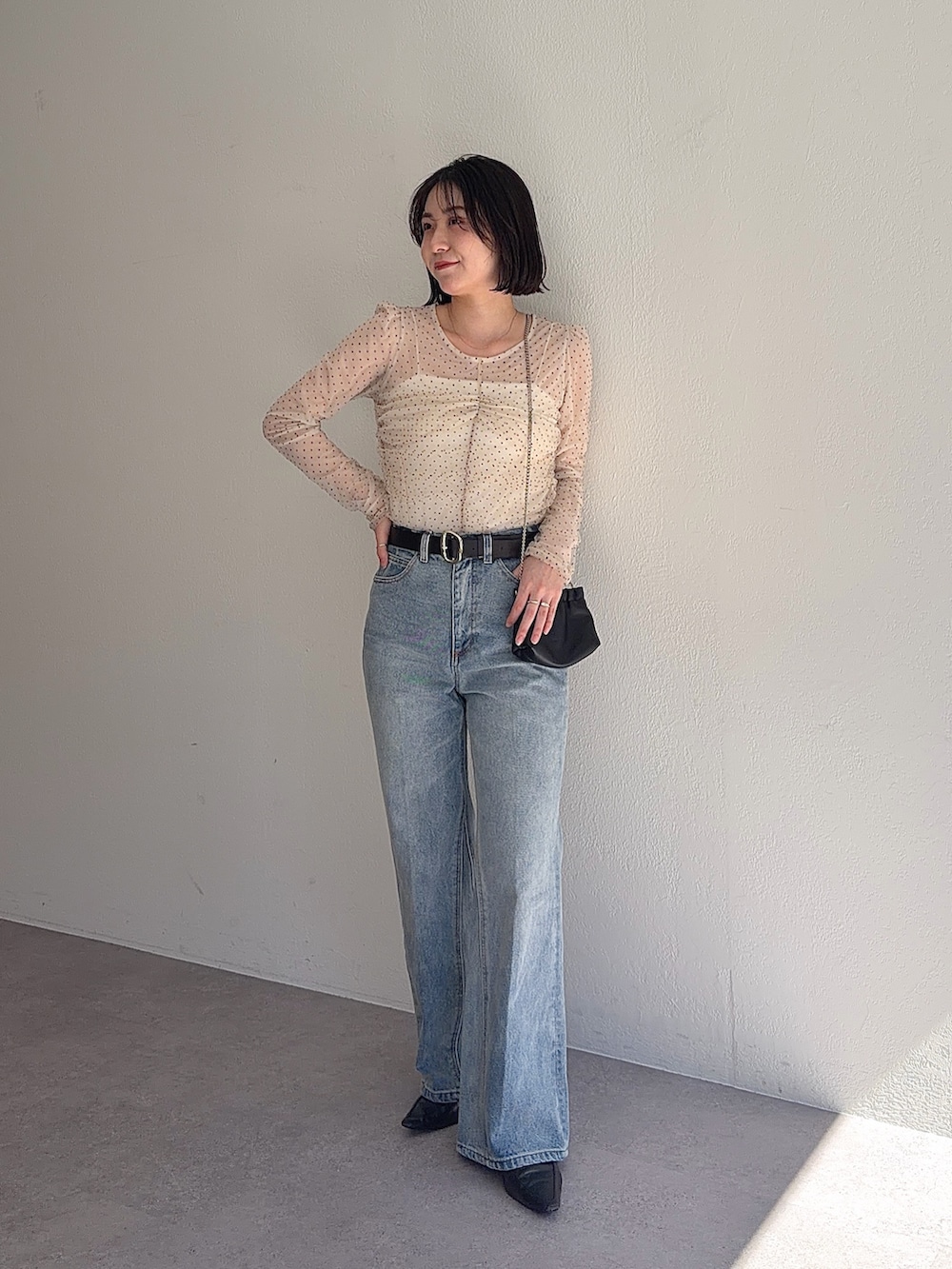 ブルー系のデニムパンツ、ブラック系のショルダーバッグ、ベージュ系のシャツ/ブラウスを着用したレディースの春コーディネートの3枚目の写真