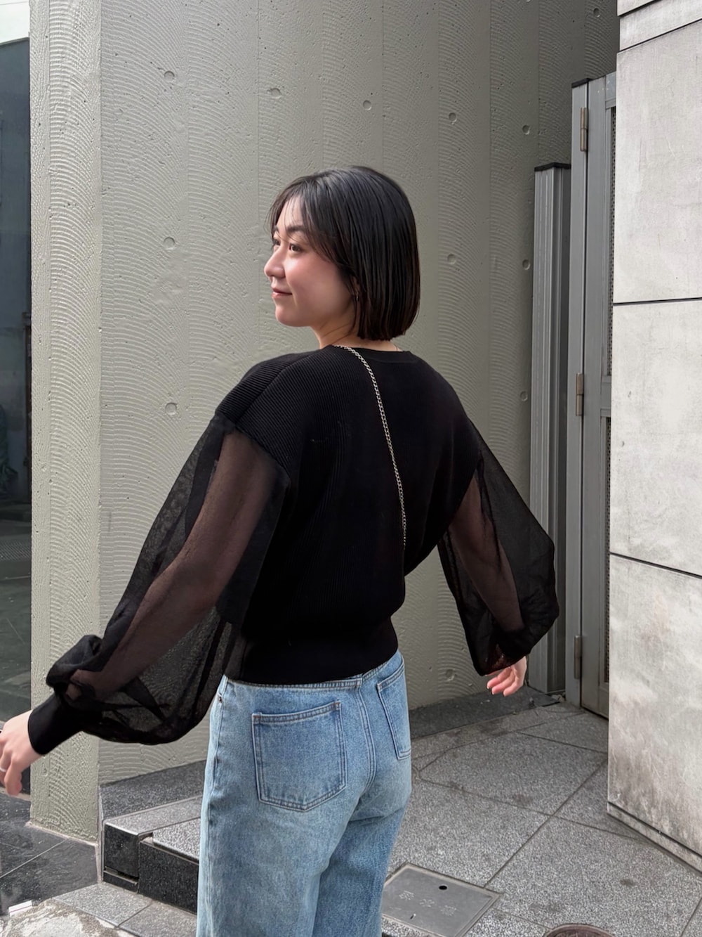 ブラック系のカーディガン/ボレロ、ブルー系のデニムパンツ、ブラック系のローファーを着用したレディースの冬コーディネートの2枚目の写真