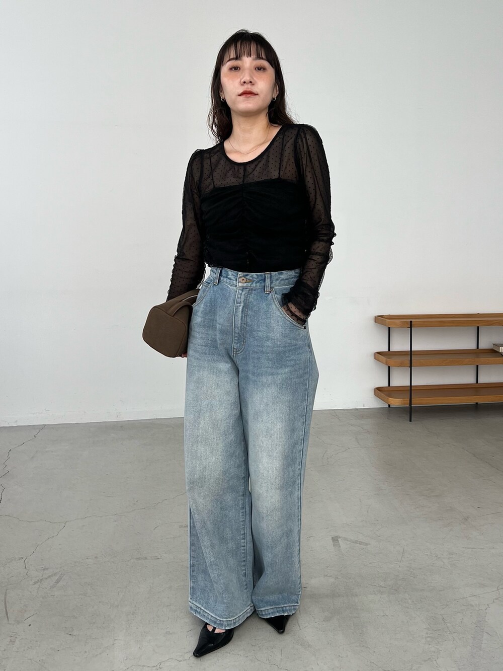 ブルー系のデニムパンツ、ブラック系のシャツ/ブラウス、ブラック系のパンプスを着用したレディースの秋コーディネートの2枚目の写真