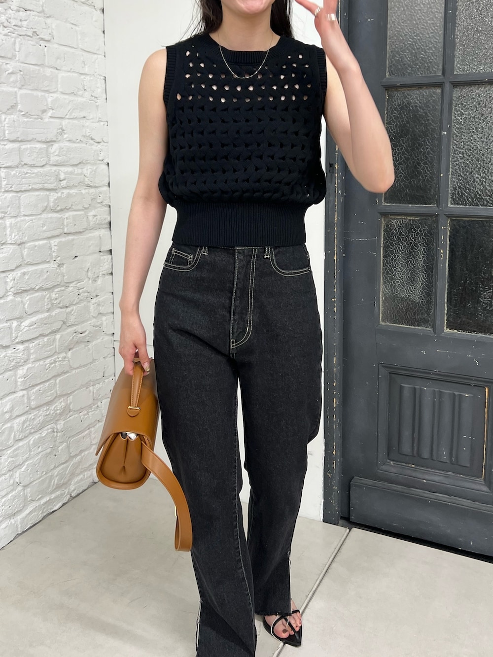 ブラック系のデニムパンツ、ブラック系のニット/セーター、ブラック系のブーツを着用したレディースの春コーディネートの4枚目の写真