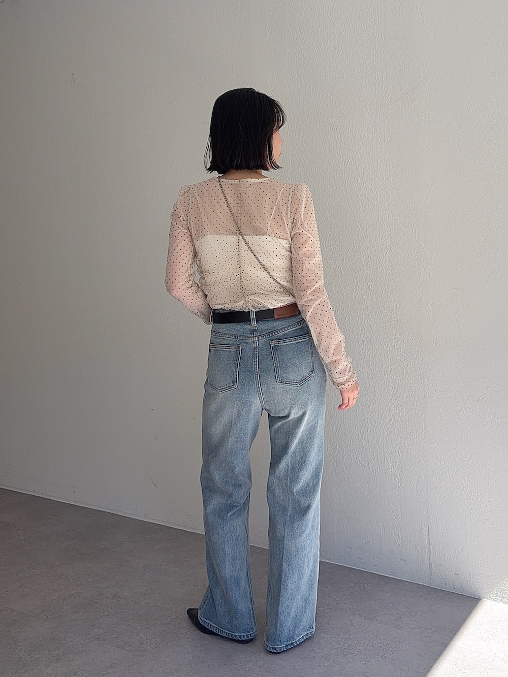 ブルー系のデニムパンツ、ブラック系のショルダーバッグ、ベージュ系のシャツ/ブラウスを着用したレディースの春コーディネートの4枚目の写真