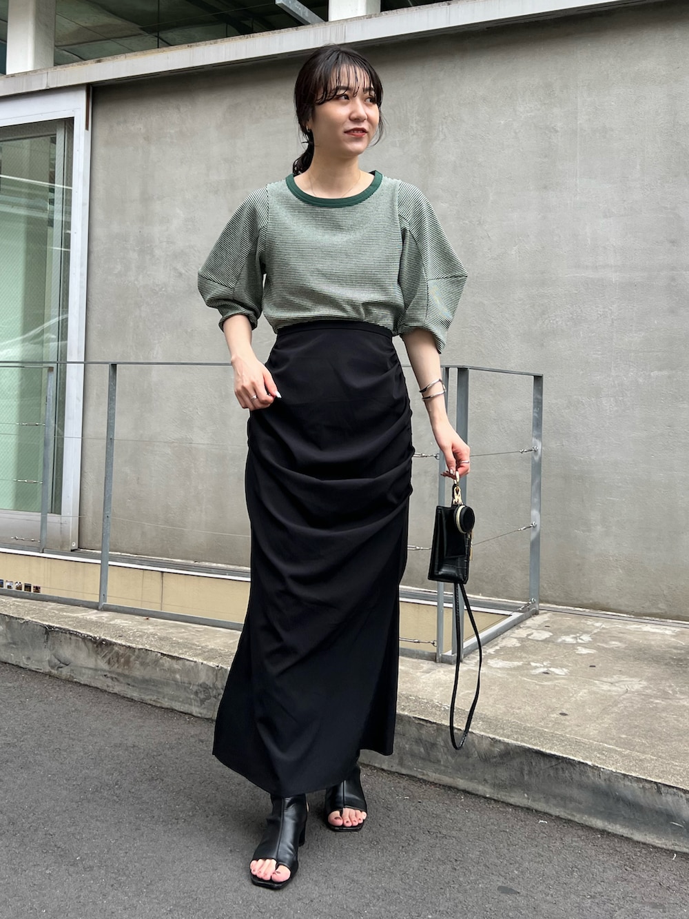 グリーン系のTシャツ/カットソー、ブラック系のスカートを着用したレディースの夏コーディネートの2枚目の写真