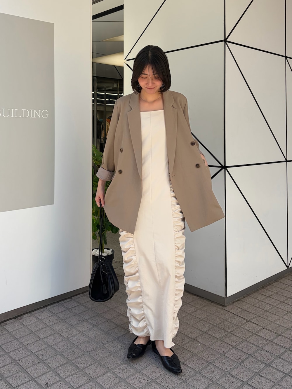 ホワイト系のワンピース、ベージュ系のテーラードジャケット、ブラック系のショルダーバッグを着用したレディースの冬コーディネートの2枚目の写真