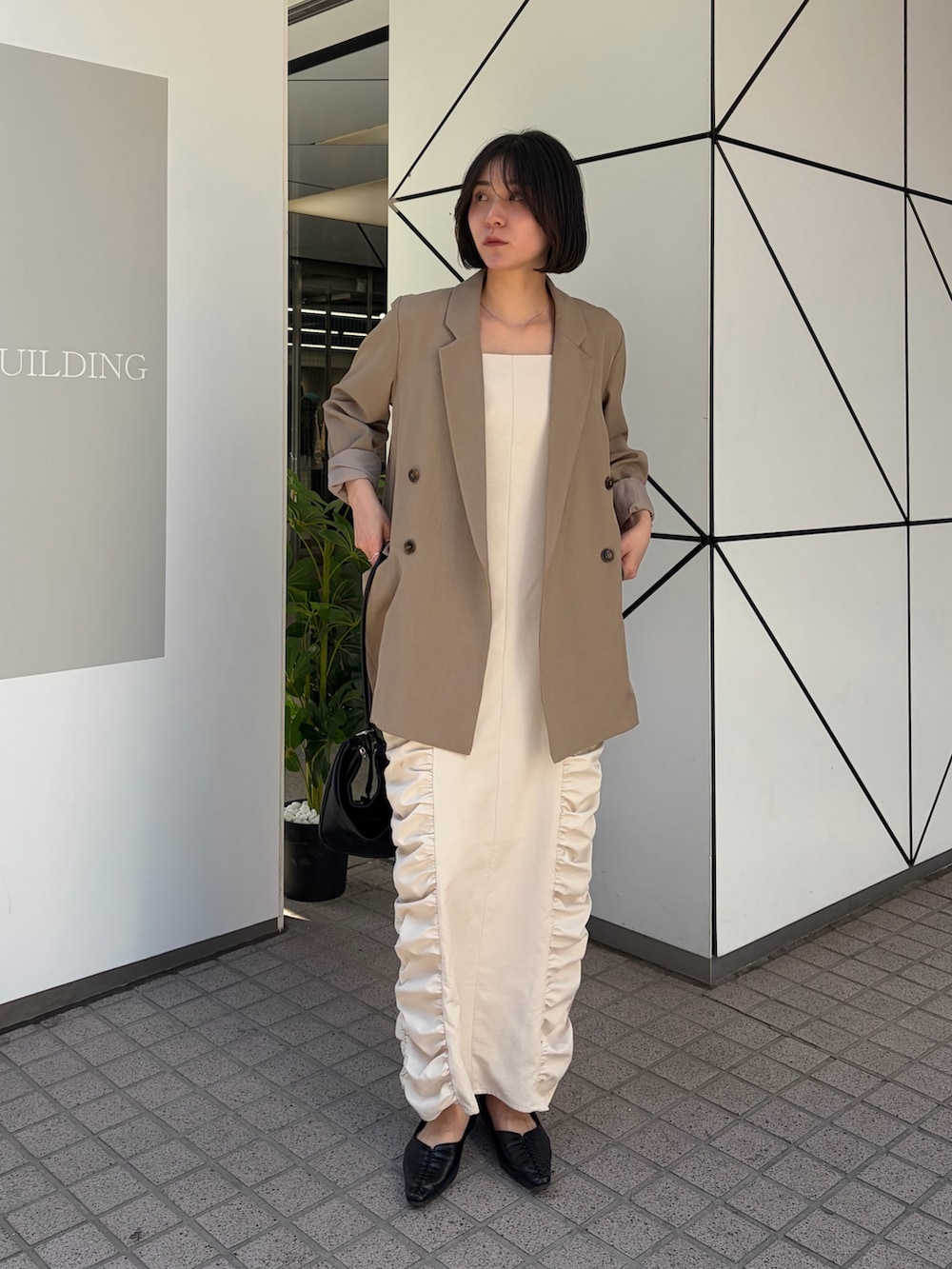 ホワイト系のワンピース、ベージュ系のテーラードジャケット、ブラック系のショルダーバッグを着用したレディースの冬コーディネートの4枚目の写真