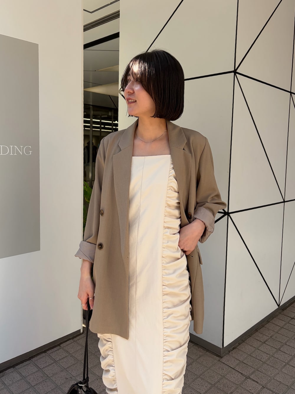 ホワイト系のワンピース、ベージュ系のテーラードジャケット、ブラック系のショルダーバッグを着用したレディースの冬コーディネートの3枚目の写真