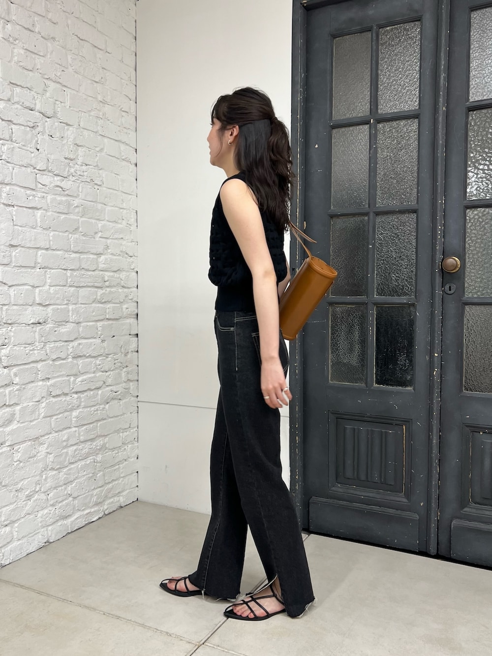 ブラック系のデニムパンツ、ブラック系のニット/セーター、ブラック系のブーツを着用したレディースの春コーディネートの2枚目の写真