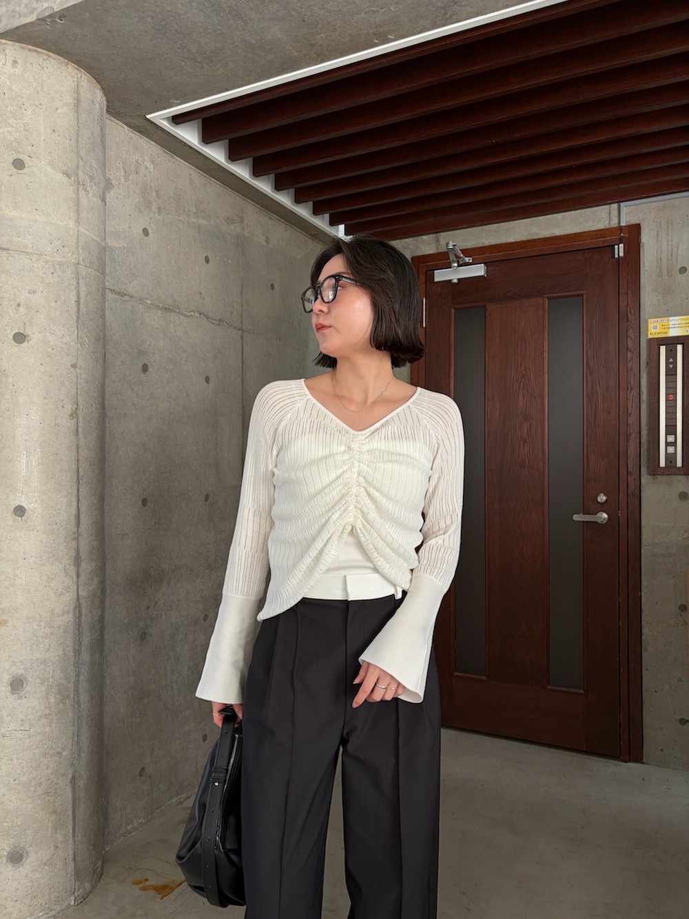 ホワイト系のニット/セーター、ホワイト系のその他パンツ、ブラック系のショルダーバッグを着用したレディースの春コーディネートの2枚目の写真