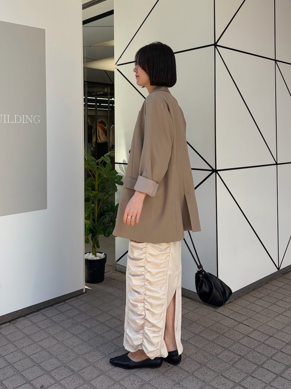 ホワイト系のワンピース、ベージュ系のテーラードジャケット、ブラック系のショルダーバッグを着用したレディースの冬コーディネートの5枚目の写真