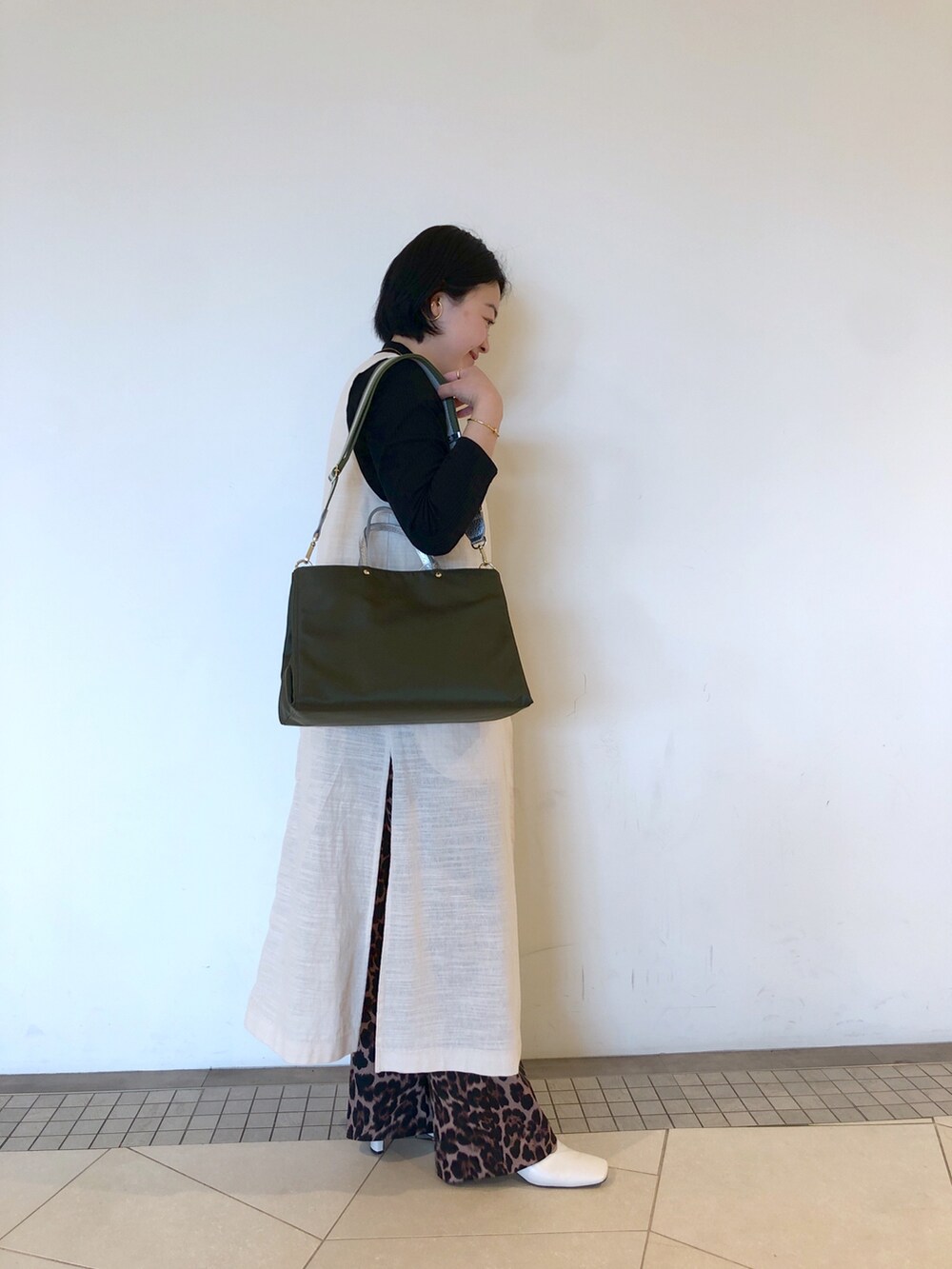 グリーン系のトートバッグ、その他のパンツ、ホワイト系のパンプスを着用したレディースの春コーディネートの2枚目の写真