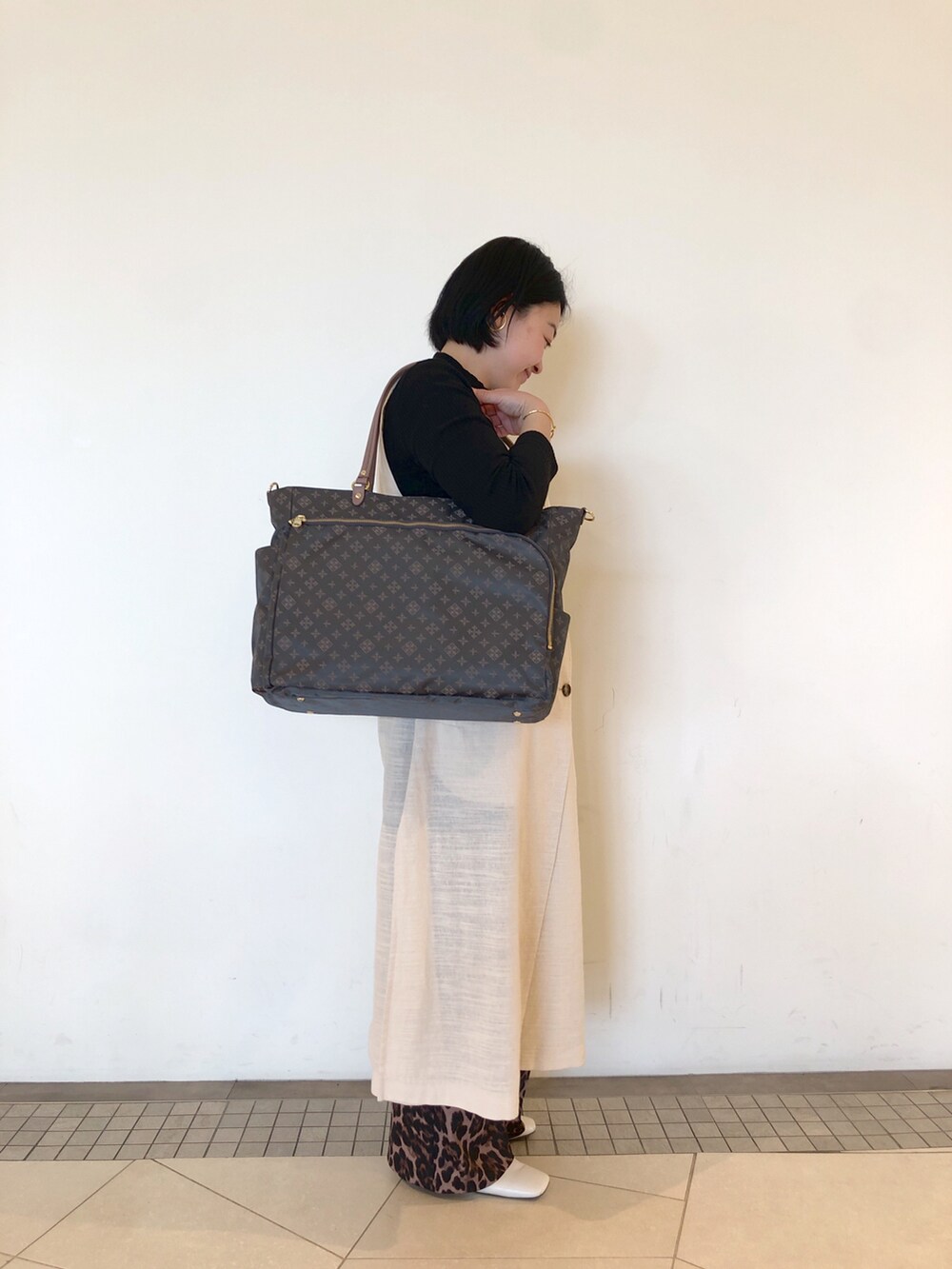 グレー系のトートバッグ、その他のパンツ、ホワイト系のパンプスを着用したレディースの冬コーディネートの3枚目の写真