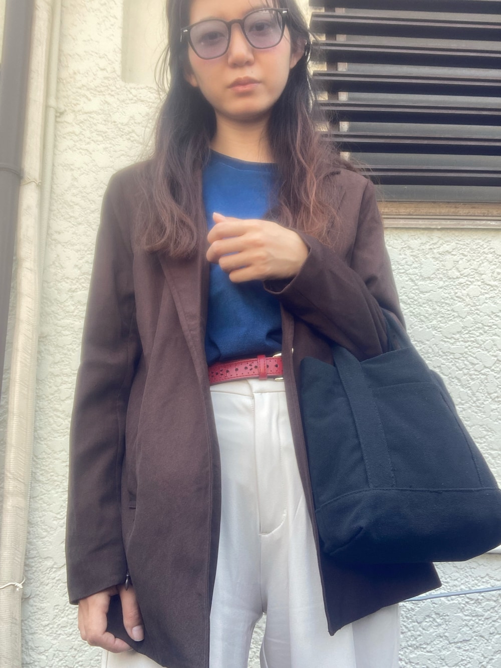 ホワイト系のスラックス、ブラウン系のノーカラージャケット、ブルー系のトップスを着用したレディースの春コーディネートの2枚目の写真