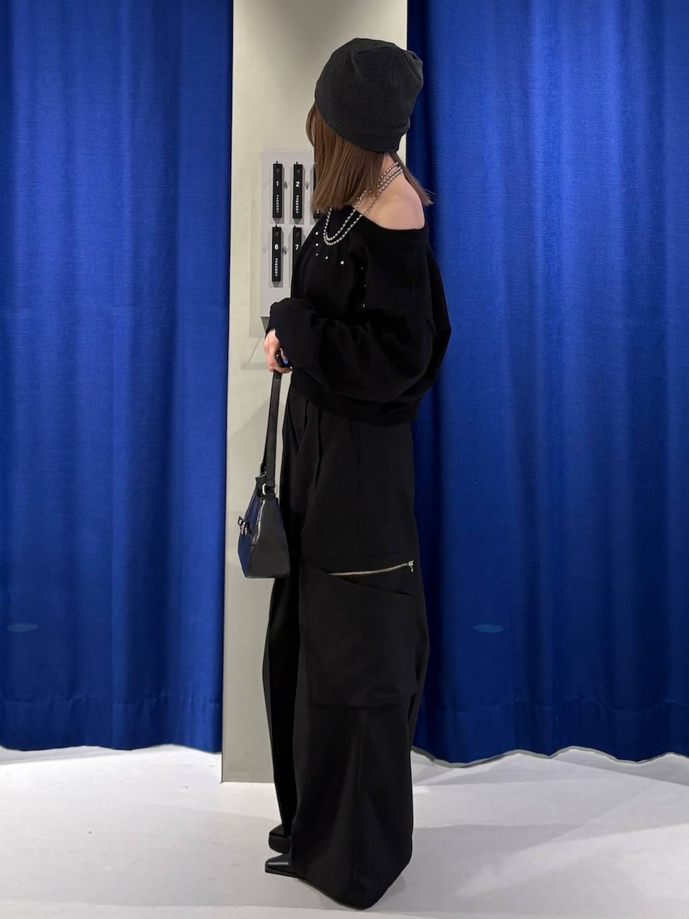 ブラック系のハンドバッグ、ブラック系のニット/セーター、ブラック系のスラックスを着用したレディースの冬コーディネートの2枚目の写真