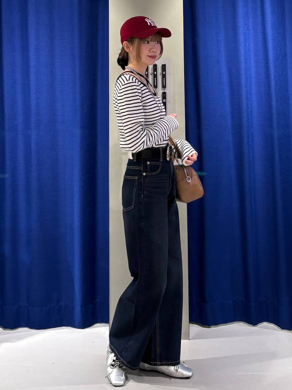 ブルー系のスラックス、ブラウン系のボストンバッグ、ホワイト系のニット/セーターを着用したレディースの冬コーディネートの2枚目の写真