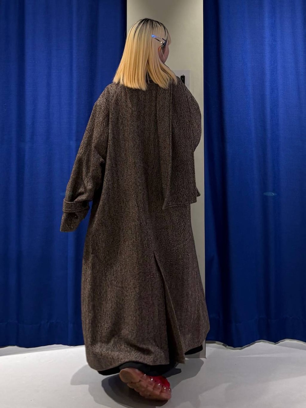 ブラウン系のチェスターコート、ブラック系のスカート、レッド系のニット/セーターを着用したレディースの冬コーディネートの3枚目の写真