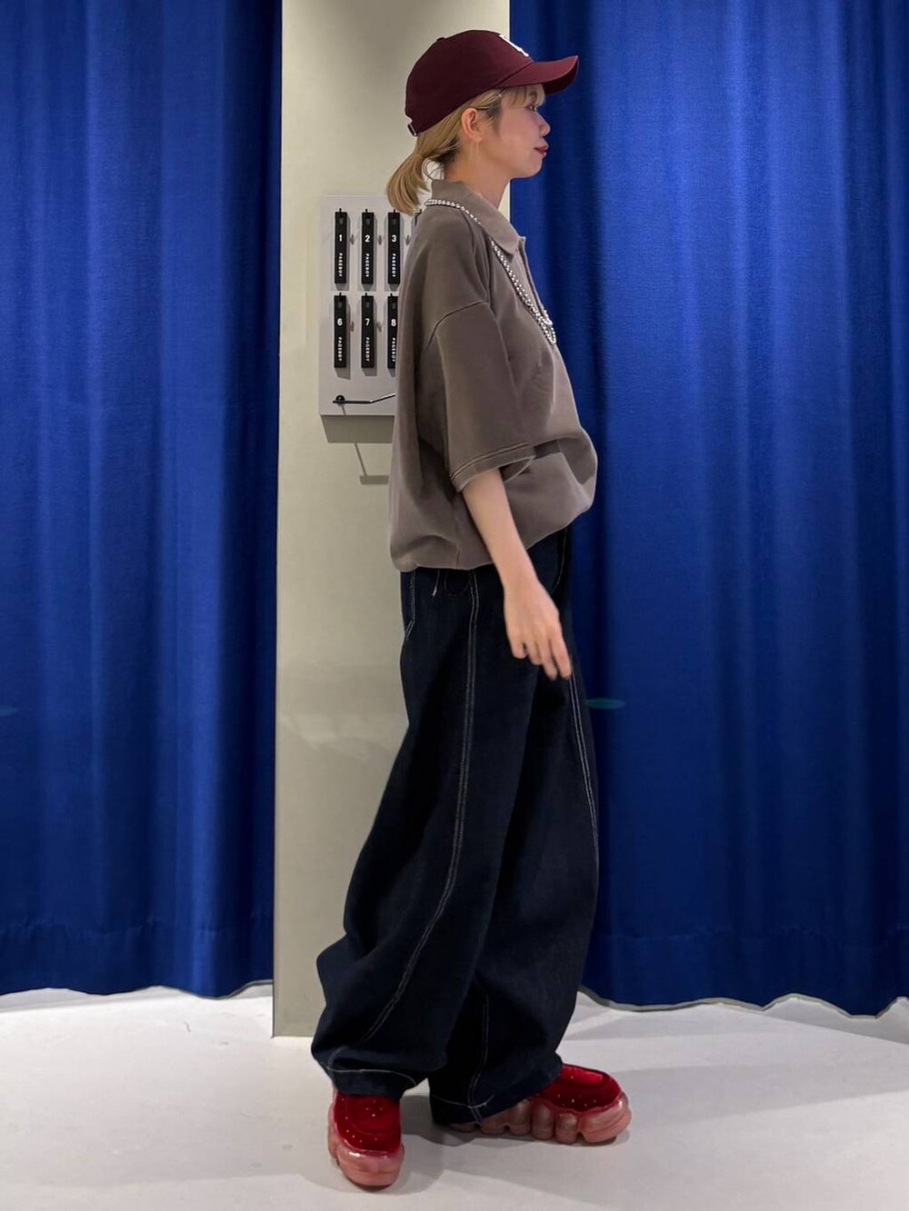 ブルー系のデニムパンツ、ブラウン系のスウェット、レッド系のキャップを着用したレディースの夏コーディネートの2枚目の写真