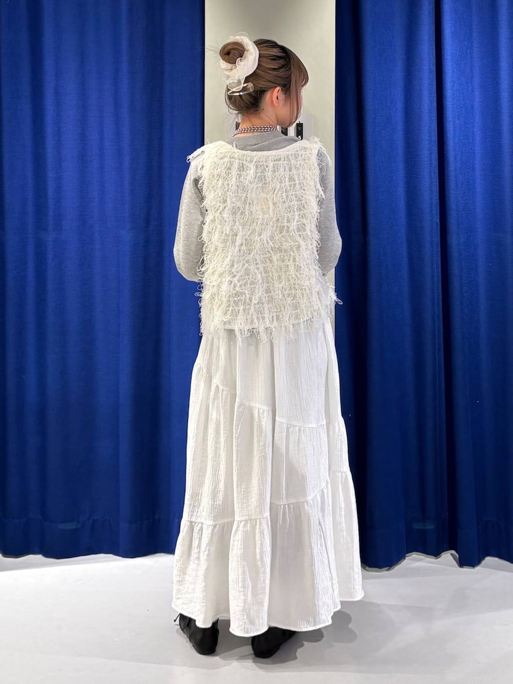 ブラウン系のボストンバッグ、ブラック系のスニーカー、ホワイト系のベストを着用したレディースの冬コーディネートの3枚目の写真