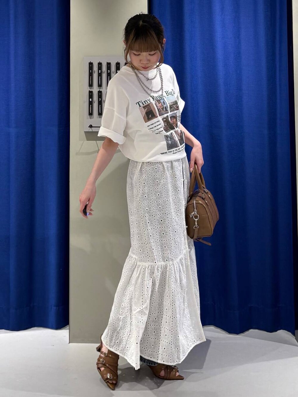 ブルー系のデニムパンツ、ブラウン系のボストンバッグ、ホワイト系のTシャツ/カットソーを着用したレディースの春コーディネートの2枚目の写真