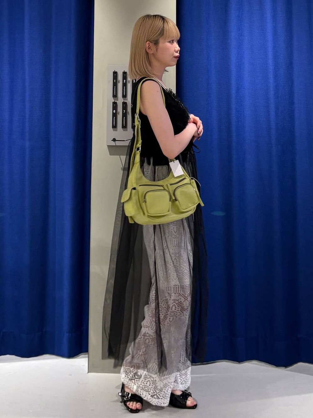 ブラック系のタンクトップ、グリーン系のショルダーバッグ、ブラック系のサンダルを着用したレディースの夏コーディネートの2枚目の写真