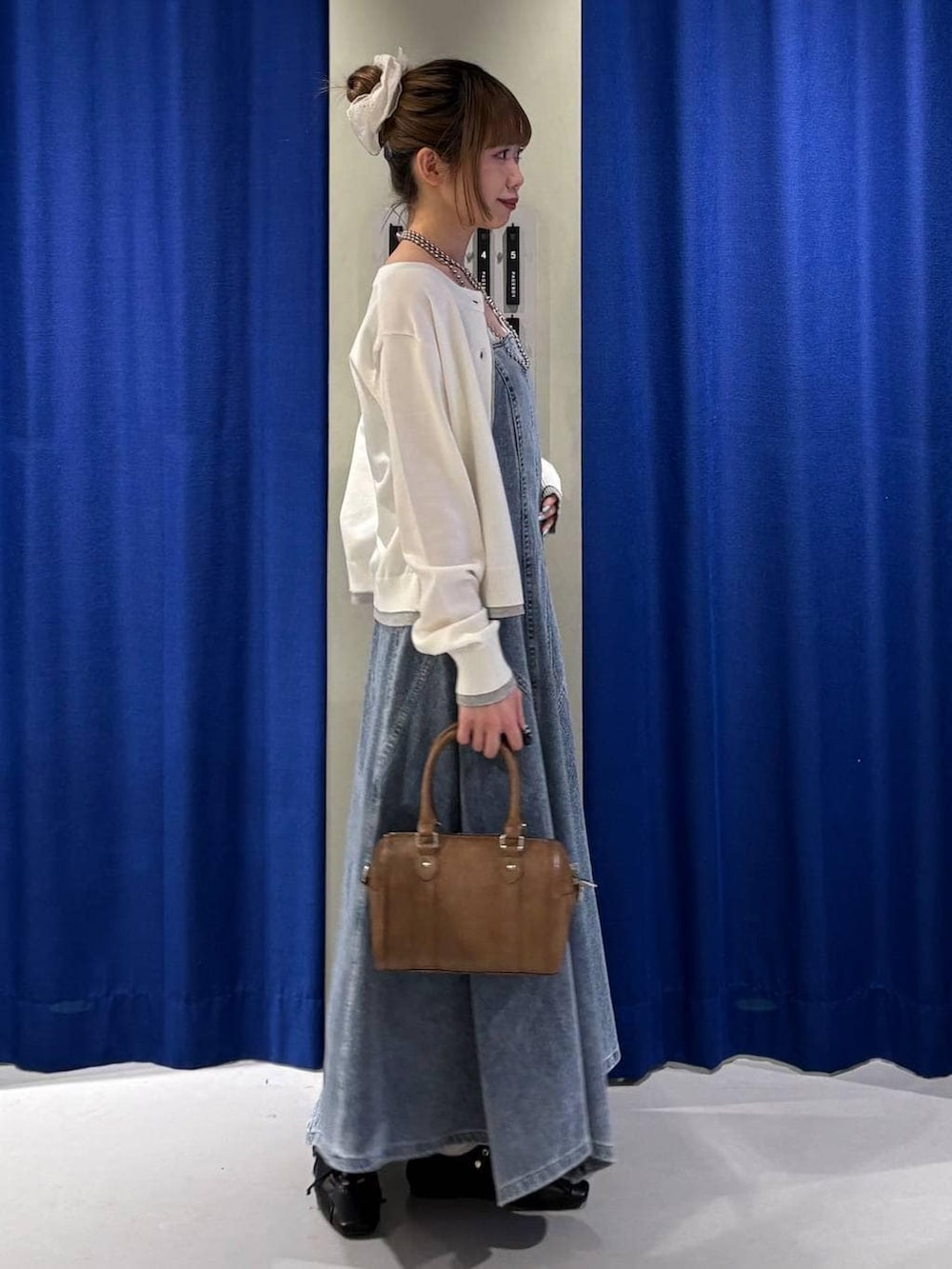 ホワイト系のキャミソール、ブラウン系のボストンバッグ、ブラック系のスニーカーを着用したレディースの冬コーディネートの2枚目の写真