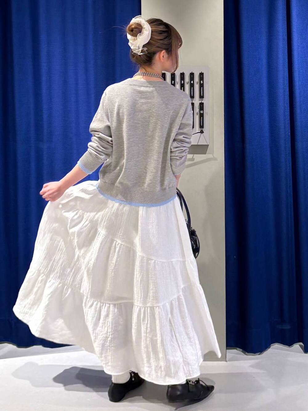 ブルー系のハンドバッグ、ブラック系のスニーカー、グレー系のカーディガン/ボレロを着用したレディースの冬コーディネートの3枚目の写真