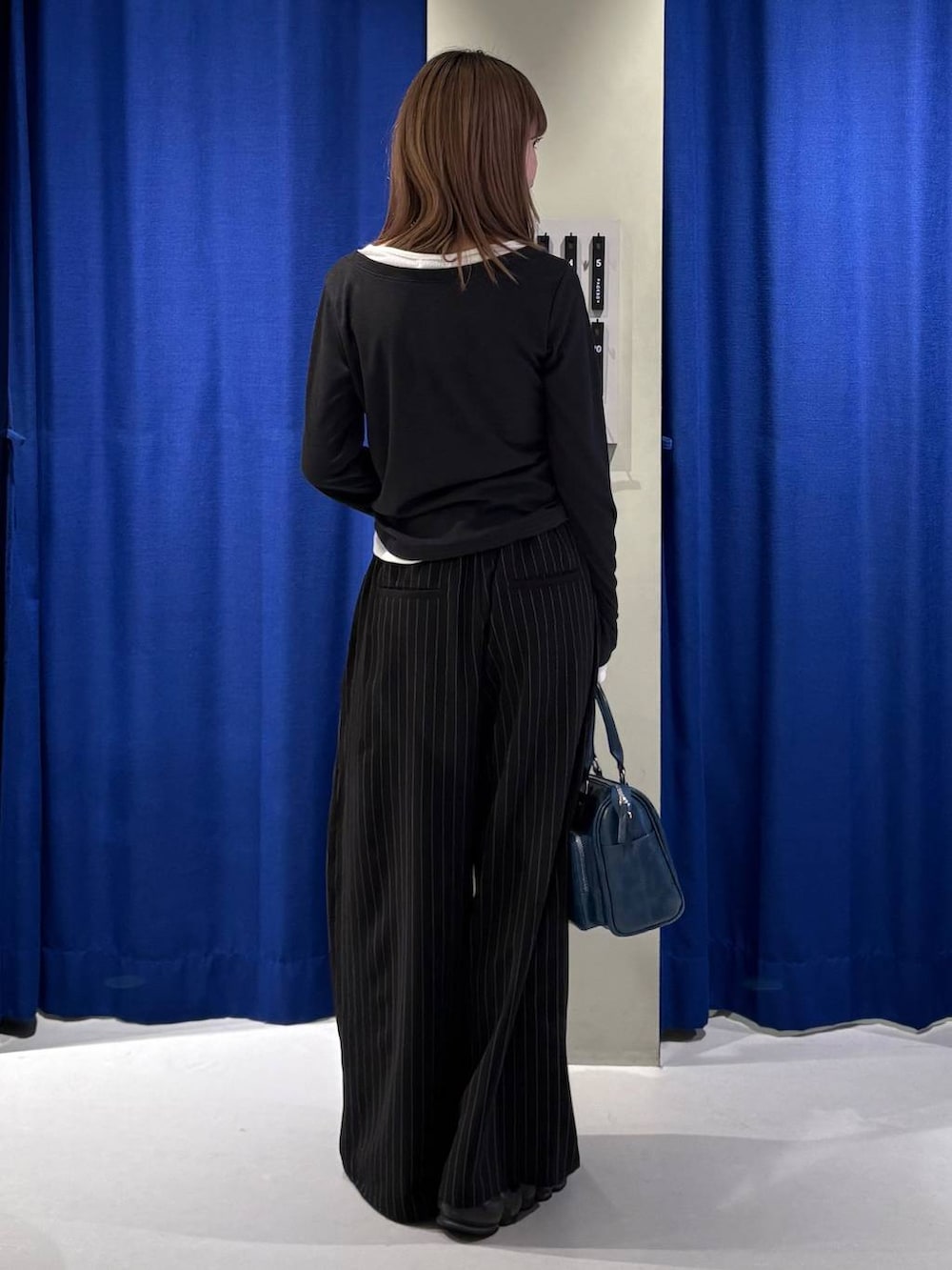 グレー系のショルダーバッグ、ブラック系のスラックス、ブラック系のTシャツ/カットソーを着用したレディースの冬コーディネートの3枚目の写真