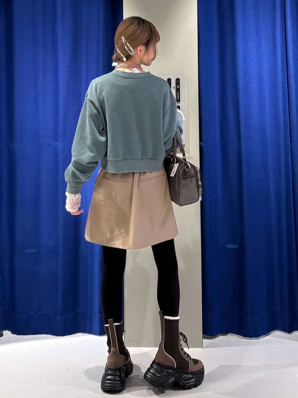 ブラウン系のブーツ、ホワイト系のTシャツ/カットソー、グリーン系のスウェットを着用したレディースの冬コーディネートの3枚目の写真