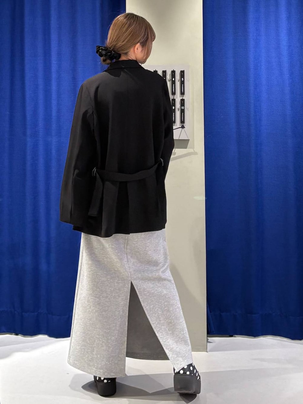 グレー系のスカート、ブラック系のニット/セーター、ブラック系のテーラードジャケットを着用したレディースの冬コーディネートの3枚目の写真