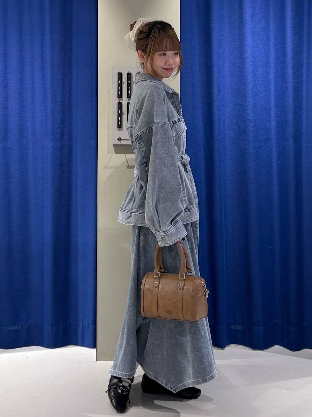 ブラウン系のボストンバッグ、ブルー系のブルゾン、ブラック系のスニーカーを着用したレディースの冬コーディネートの2枚目の写真