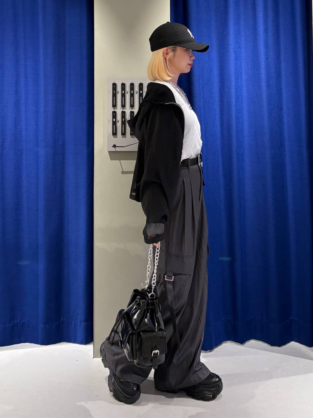 ブラック系のスニーカー、ホワイト系のTシャツ/カットソー、ブラック系のショルダーバッグを着用したレディースの秋コーディネートの2枚目の写真