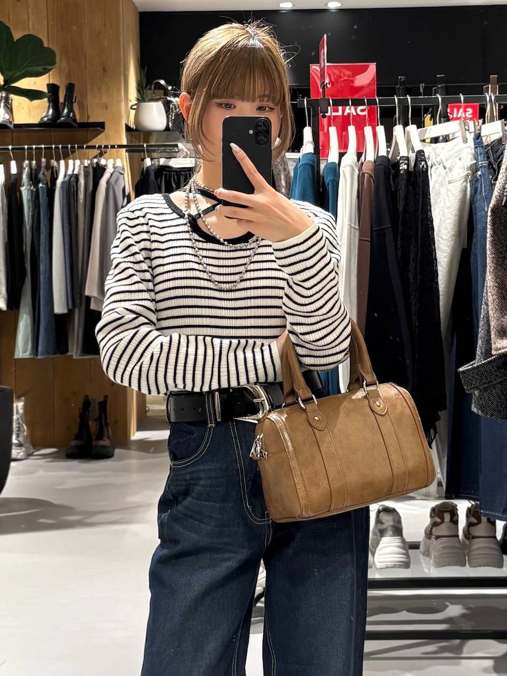 ブルー系のスラックス、ブラウン系のボストンバッグ、ホワイト系のニット/セーターを着用したレディースの冬コーディネートの4枚目の写真