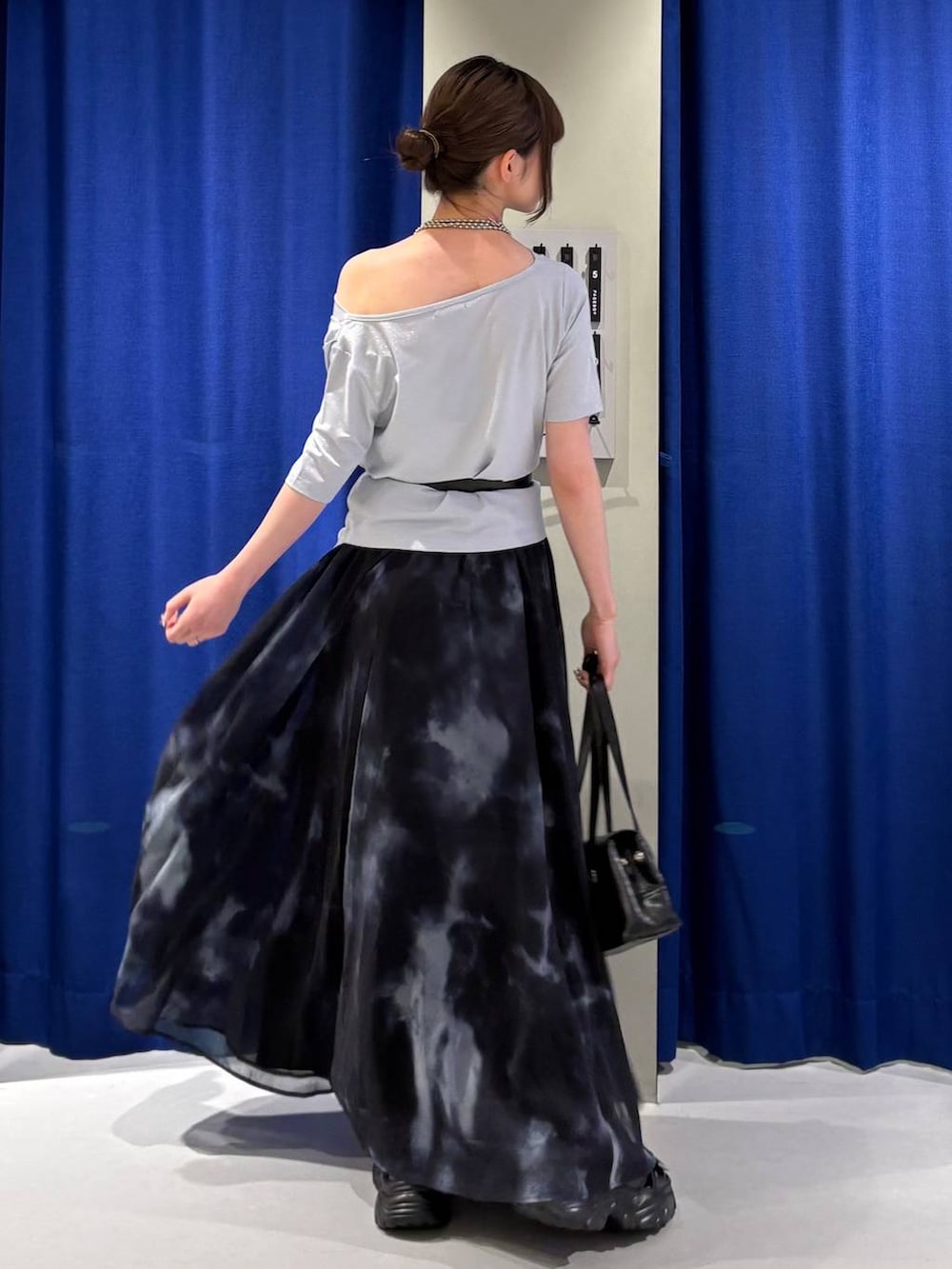グレー系のスカート、ブラック系のサンダル、ベージュ系のTシャツ/カットソーを着用したレディースの夏コーディネートの3枚目の写真